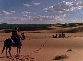 Movie still from “Arabian Nights” (1942), directed by John Rawlins – A group of people riding horses in the desert; Extreme Wide shot, High angle