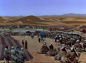 Movie still from “Arabian Nights” (1942), directed by John Rawlins – A group of people gathered in the desert for an event; Extreme Wide shot, High angle