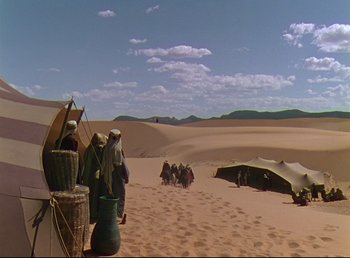 Movie still from “Arabian Nights” (1942), directed by John Rawlins – A group of people are standing in the desert; Extreme Wide shot, High angle