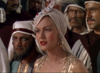 Movie still from “Arabian Nights” (1942), directed by John Rawlins – A woman in a white headdress and a group of men; Close Up shot, Over the shoulder angle