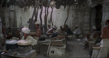 Movie still from “Arabian Nights” (1974), directed by Pier Paolo Pasolini – A group of men sitting at a table with food; Wide shot, High angle
