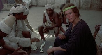 Movie still from “Arabian Nights” (1974), directed by Pier Paolo Pasolini – A group of men sitting around a table playing dominoes; Medium shot, High angle