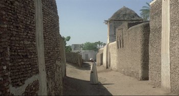 Movie still from “Arabian Nights” (1974), directed by Pier Paolo Pasolini – A man in a white robe walking down a street; Extreme Wide shot, Low angle
