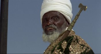 Movie still from “Arabian Nights” (1974), directed by Pier Paolo Pasolini – An old man with a white turban and a white beard; Close Up shot, Low angle