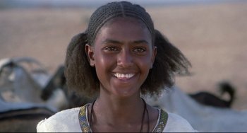 Movie still from “Arabian Nights” (1974), directed by Pier Paolo Pasolini – A young woman smiles brightly for the camera; Close Up shot, Over the shoulder angle
