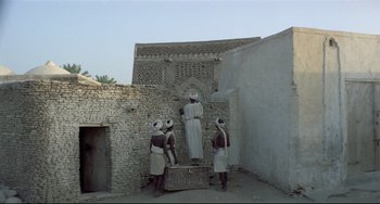 Movie still from “Arabian Nights” (1974), directed by Pier Paolo Pasolini – A group of men standing next to each other in front of a building; Extreme Wide shot, Low angle