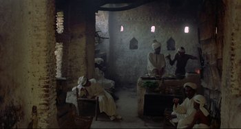 Movie still from “Arabian Nights” (1974), directed by Pier Paolo Pasolini – A group of people in a room cooking food; Wide shot, High angle