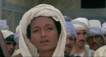 Movie still from “Arabian Nights” (1974), directed by Pier Paolo Pasolini – A group of people in a row with a man in the background; Close Up shot, Over the shoulder angle