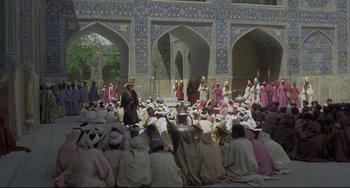 Movie still from “Arabian Nights” (1974), directed by Pier Paolo Pasolini – A group of people sitting in front of a building; Extreme Wide shot, High angle