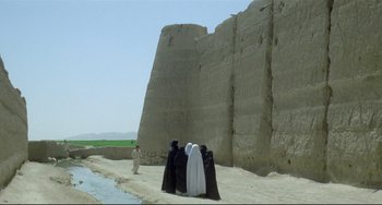 Movie still from “Arabian Nights” (1974), directed by Pier Paolo Pasolini – A group of people standing in front of a stone wall; Extreme Wide shot, Low angle
