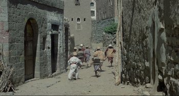 Movie still from “Arabian Nights” (1974), directed by Pier Paolo Pasolini – A group of people walking down a dirt road; Extreme Wide shot, High angle