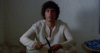 Movie still from “Arabian Nights” (1974), directed by Pier Paolo Pasolini – A man in a white shirt holding a knife; Medium shot, Low angle