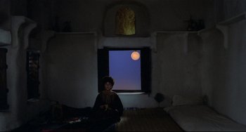 Movie still from “Arabian Nights” (1974), directed by Pier Paolo Pasolini – A woman sitting in front of a window with a moon in the window; Extreme Wide shot, High angle