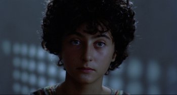 Movie still from “Arabian Nights” (1974), directed by Pier Paolo Pasolini – A young woman with curly black hair looking at the camera; Close Up shot, High angle