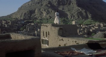 Movie still from “Arabian Nights” (1974), directed by Pier Paolo Pasolini – A man standing on top of a building in the middle of the desert; Extreme Wide shot, Low angle