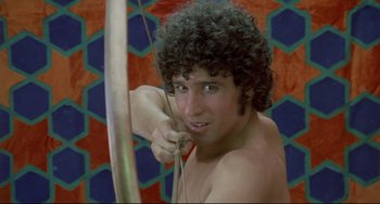 Movie still from “Arabian Nights” (1974), directed by Pier Paolo Pasolini – A man with curly hair is holding a bow and arrow; Close Up shot, Low angle