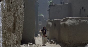 Movie still from “Arabian Nights” (1974), directed by Pier Paolo Pasolini – A man standing in the middle of an alley way; Wide shot, Low angle