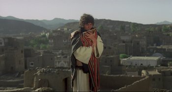 Movie still from “Arabian Nights” (1974), directed by Pier Paolo Pasolini – A man dressed as jesus is holding a blanket over his face; Wide shot, Over the shoulder angle