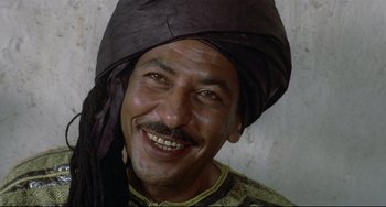 Movie still from “Arabian Nights” (1974), directed by Pier Paolo Pasolini – A man wearing a turban smiling for the camera; Close Up shot, High angle