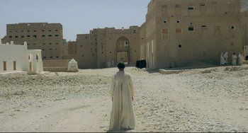 Movie still from “Arabian Nights” (1974), directed by Pier Paolo Pasolini – A man in a white robe standing in front of a building; Extreme Wide shot, Low angle