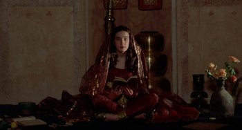 Movie still from “Arabian Nights” (1974), directed by Pier Paolo Pasolini – A woman in a red dress is reading a book; Medium shot, High angle