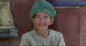 Movie still from “Arabian Nights” (1974), directed by Pier Paolo Pasolini – An old man wearing a green turban is smiling for the camera; Close Up shot, High angle