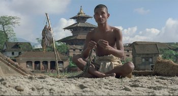 Movie still from “Arabian Nights” (1974), directed by Pier Paolo Pasolini – A man sitting on the ground with a bird hanging from it; Wide shot, Low angle