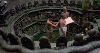 Movie still from “Arabian Nights” (1974), directed by Pier Paolo Pasolini – A group of men standing in a circle with statues; Wide shot, High angle