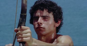 Movie still from “Arabian Nights” (1974), directed by Pier Paolo Pasolini – A young man holding onto a bamboo stick; Close Up shot, Low angle