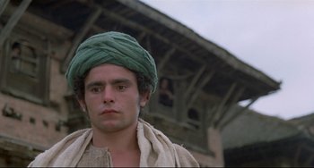Movie still from “Arabian Nights” (1974), directed by Pier Paolo Pasolini – A man with a green turban is standing in front of a building; Close Up shot, Low angle