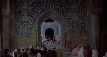 Movie still from “Arabian Nights” (1974), directed by Pier Paolo Pasolini – A group of people sitting in front of an archway; Extreme Wide shot, High angle