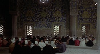 Movie still from “Arabian Nights” (1974), directed by Pier Paolo Pasolini – A group of people sitting around a table; Extreme Wide shot, High angle