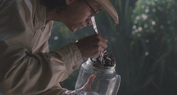 Movie still from “Arachnophobia” (1990), directed by Frank Marshall – A man holding a jar with a bunch of sticks in it; Close Up shot, Low angle