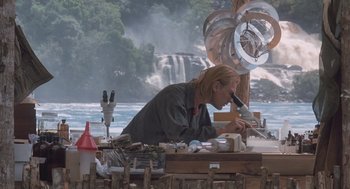 A man working on a piece of art in front of a body of water
