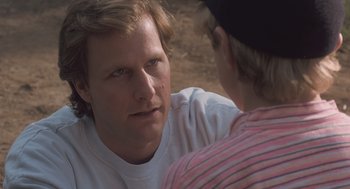 Movie still from “Arachnophobia” (1990), directed by Frank Marshall – A man sitting next to another man on a dirt ground; Close Up shot, Over the shoulder angle