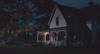 Movie still from “Arachnophobia” (1990), directed by Frank Marshall – A white house with a porch lit up at night; Extreme Wide shot, Low angle