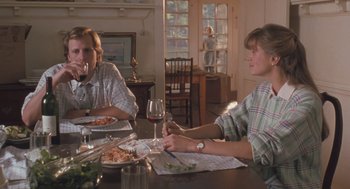 Movie still from “Arachnophobia” (1990), directed by Frank Marshall – Two people sitting at a dinner table with plates of food; Medium shot, Over the shoulder angle