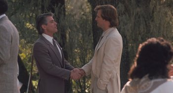 Movie still from “Arachnophobia” (1990), directed by Frank Marshall – Two men in suits shaking hands in front of trees; Medium shot, Over the shoulder angle
