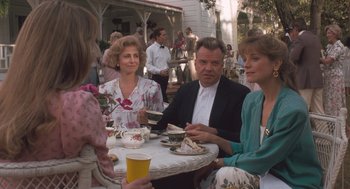 Movie still from “Arachnophobia” (1990), directed by Frank Marshall – A group of people sitting at a table with drinks; Medium shot, Over the shoulder angle