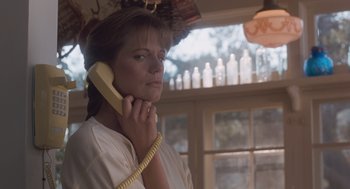 Movie still from “Arachnophobia” (1990), directed by Frank Marshall – A woman holding a phone to her ear while standing in front of a window; Close Up shot, Low angle