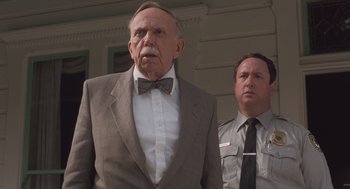 Movie still from “Arachnophobia” (1990), directed by Frank Marshall – An older man wearing a suit and a bow tie standing in front of another man; Close Up shot, Low angle