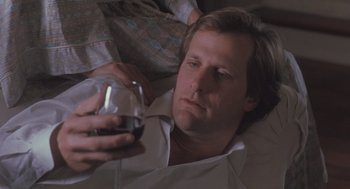 Movie still from “Arachnophobia” (1990), directed by Frank Marshall – A man holding a wine glass while lying on the floor; Close Up shot, High angle