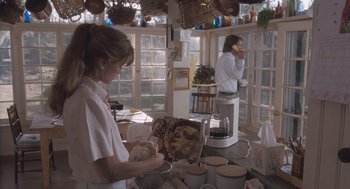 Movie still from “Arachnophobia” (1990), directed by Frank Marshall – A woman in a kitchen holding a bowl and talking on the phone; Wide shot, Low angle