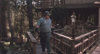 Movie still from “Arachnophobia” (1990), directed by Frank Marshall – A man walking down a wooden bridge near some trees; Wide shot, Low angle