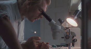 Movie still from “Arachnophobia” (1990), directed by Frank Marshall – A man looking through a magnifying glass at something on a table; Close Up shot, Over the shoulder angle