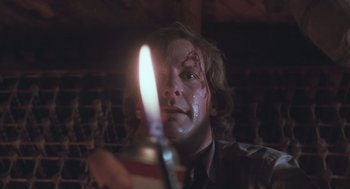 Movie still from “Arachnophobia” (1990), directed by Frank Marshall – A man with blood on his face holding a lit candle; Close Up shot, Low angle