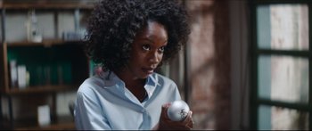 Movie still from “Archenemy” (2020), directed by Adam Egypt Mortimer – A woman holding an object in her hands; Close Up shot, Over the shoulder angle