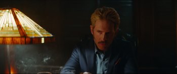 Movie still from “Archenemy” (2020), directed by Adam Egypt Mortimer – A person wearing a suit and tie; Close Up shot, Over the shoulder angle