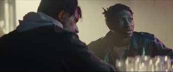 Movie still from “Archenemy” (2020), directed by Adam Egypt Mortimer – Two people sitting in a room talking to each other; Close Up shot, Over the shoulder angle