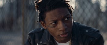 Movie still from “Archenemy” (2020), directed by Adam Egypt Mortimer – A person wearing a leather jacket; Close Up shot, Over the shoulder angle